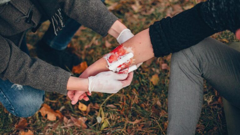 053321300_1758671840-providing-first-aid-park-man-bandaged-injured-arm-guy-helps-friend.jpg